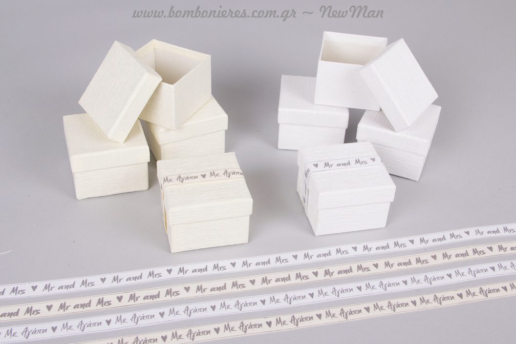 Μπομπονιέρα σε λευκό ή εκρού κουτί, διακοσμημένη με υφασμάτινη τυπωμένη κορδέλα.